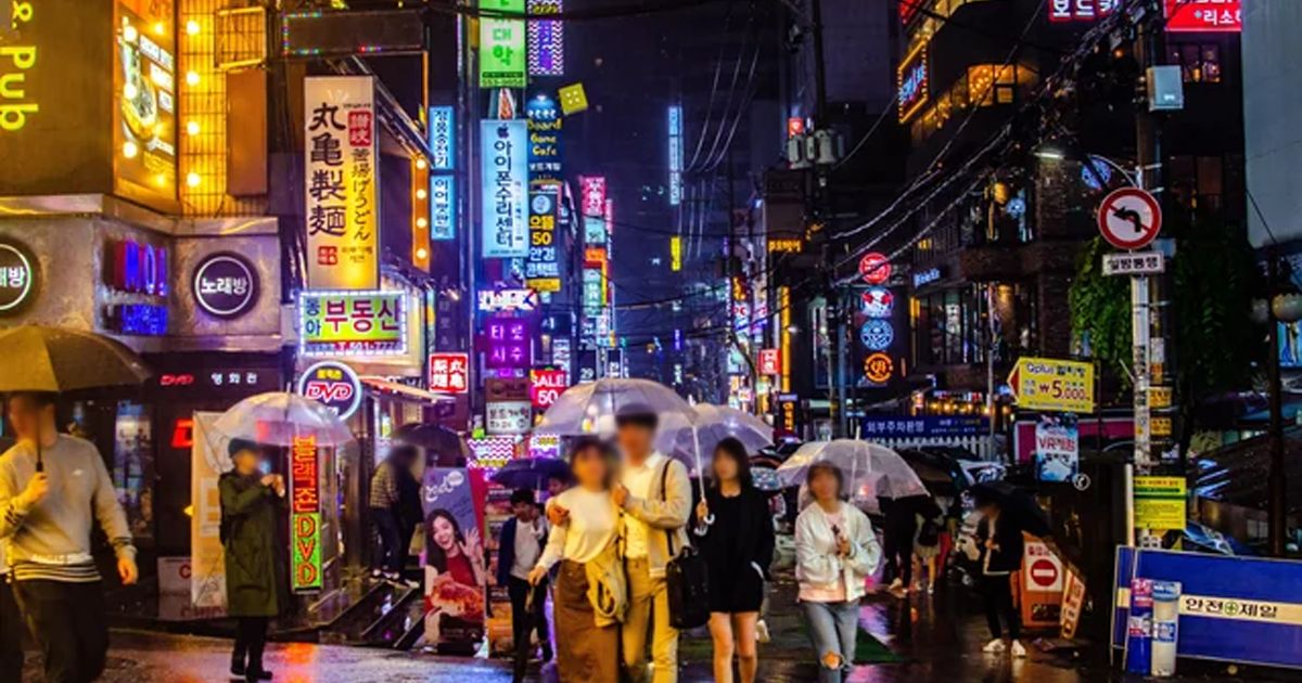 A neon-lit street in Seoul at night, representing the modern, tech-savvy environment where an underground digital economy thrives.