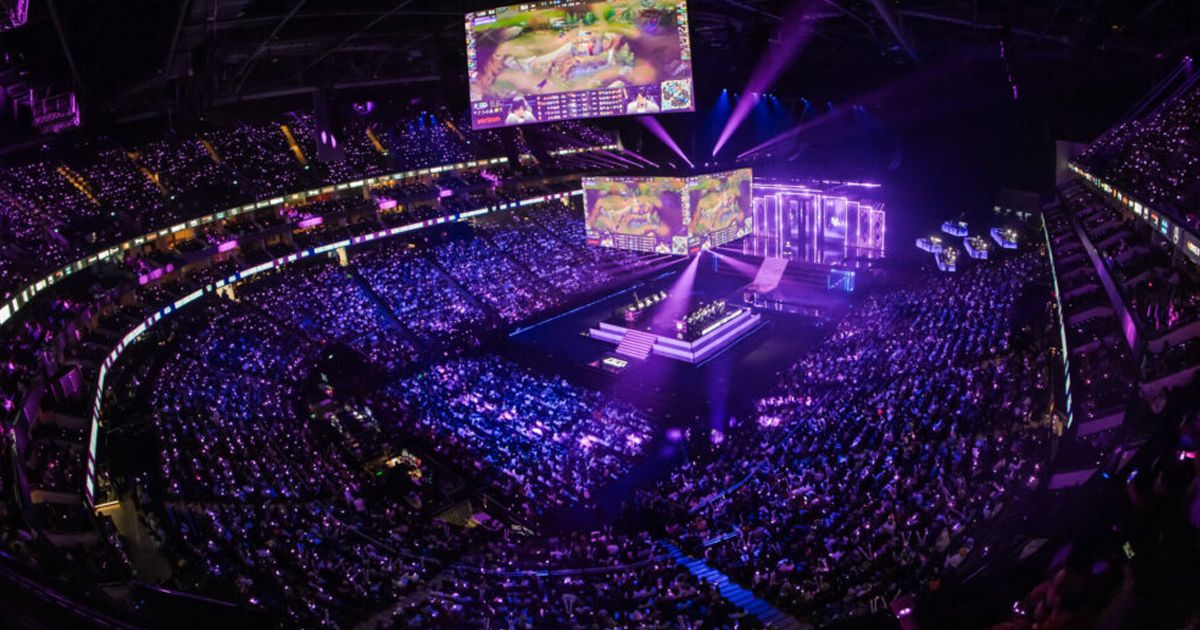 A packed eSports arena in Seoul with thousands of fans watching a League of Legends tournament on massive screens.