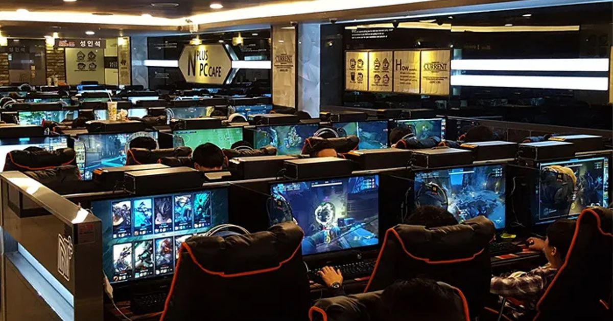 Interior of a modern Korean PC bang with rows of gaming computers and LED lighting, showing the social gaming culture.